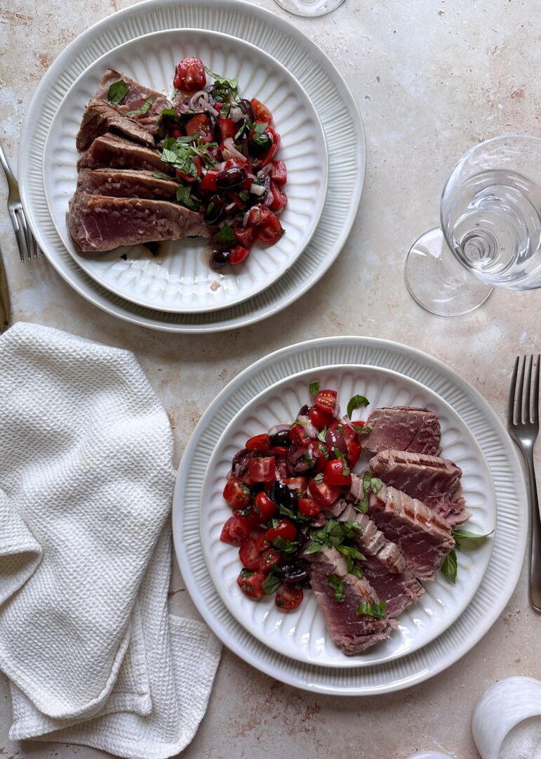 two plates of sliced mediterranean tuna with tomato salad on the side