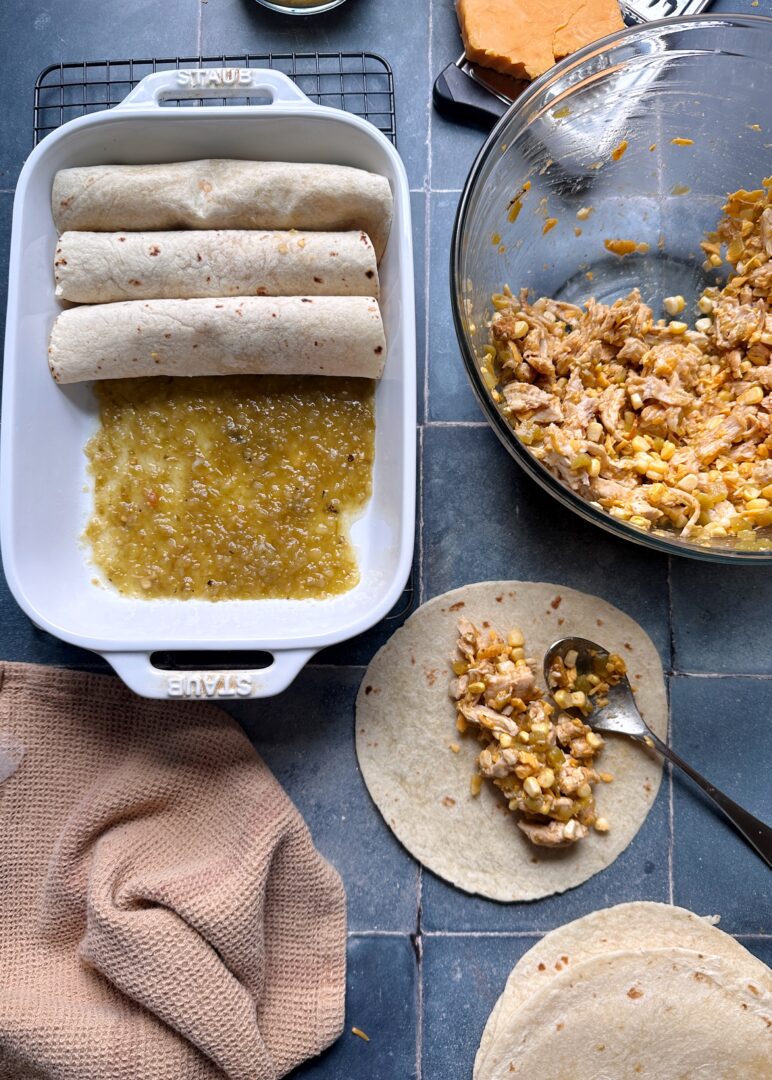 assembling green chile chicken enchiladas in casserole dish