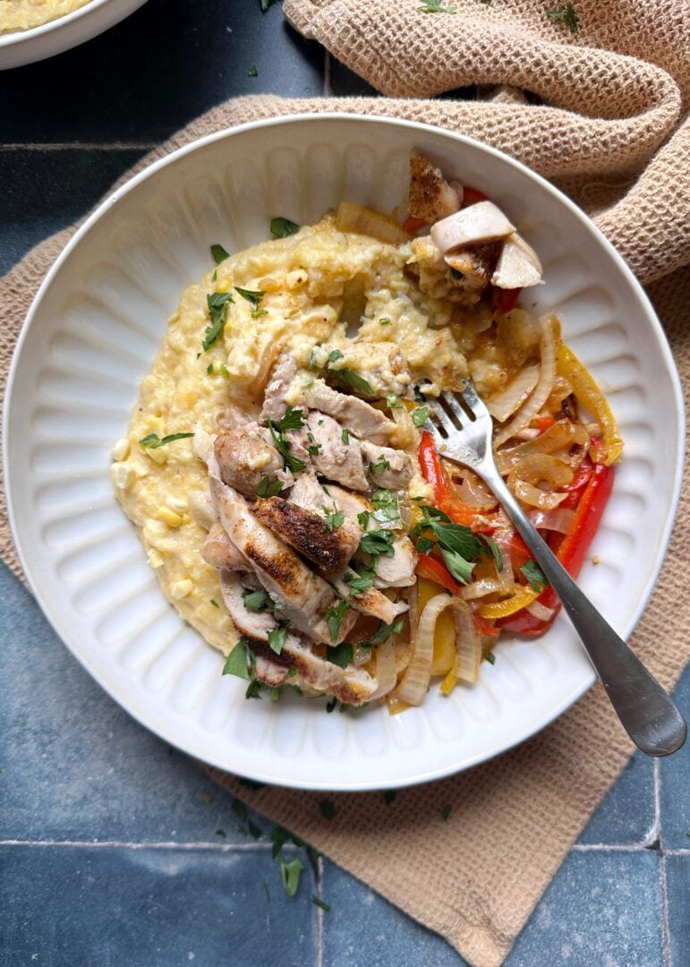 bowl of Cajun chicken peppers and onions with cheesy polenta with a fork