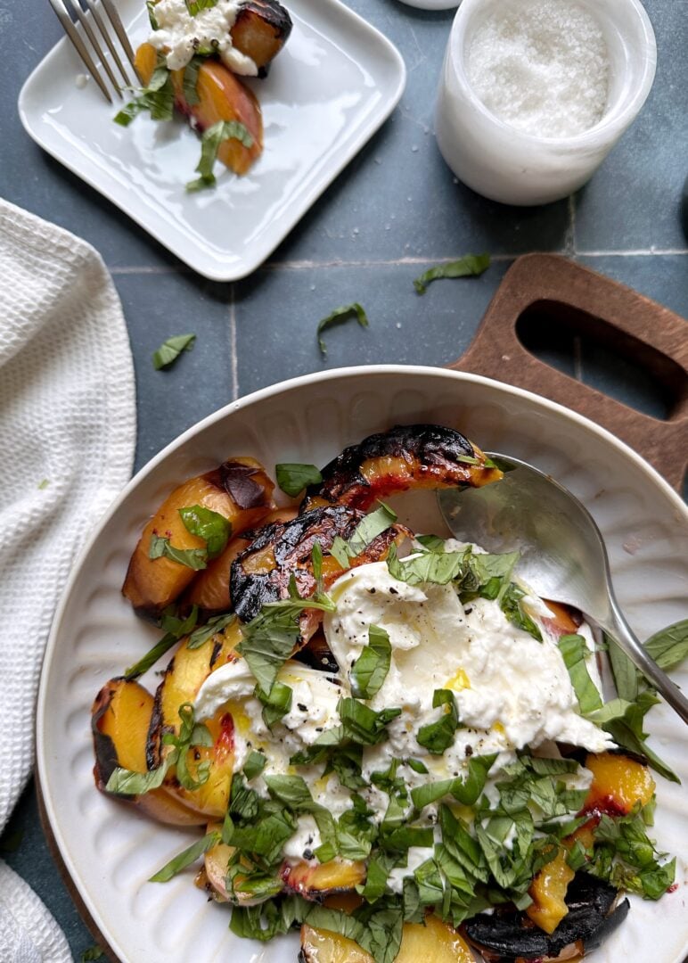 bowl of grilled peach and burrata salad with serving on the side