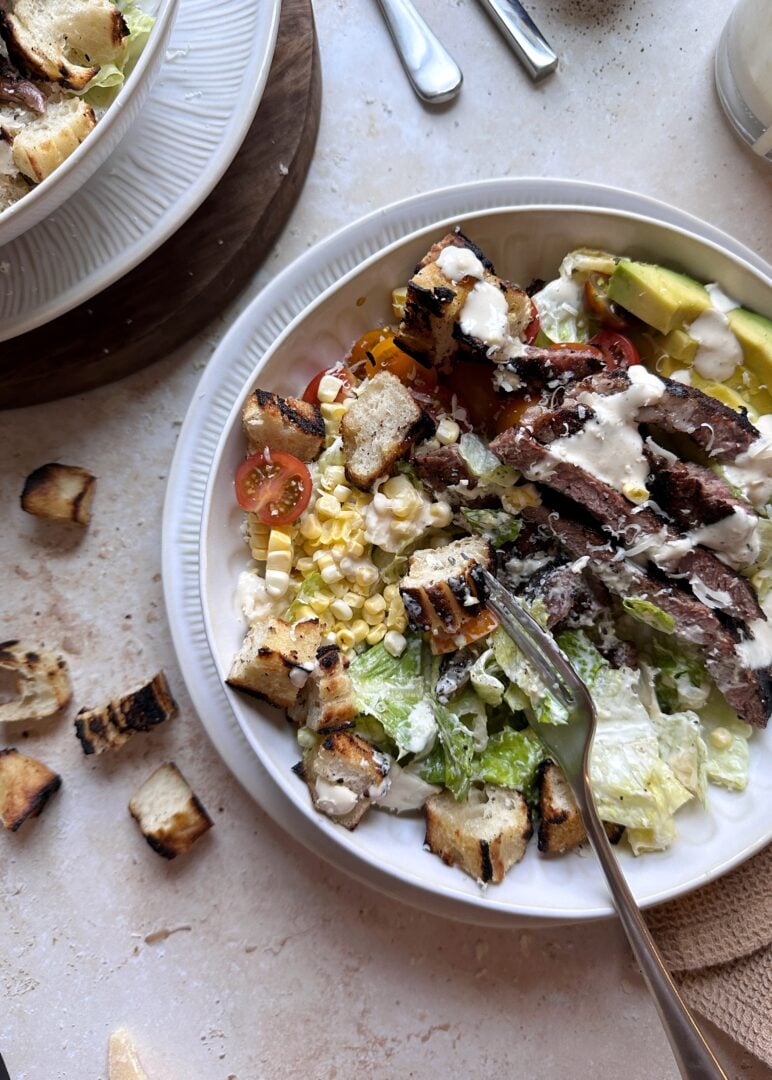 bowl of grilled steak caesar salad with silver fork