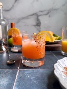 glass of orange aperol margarita with tajin rim