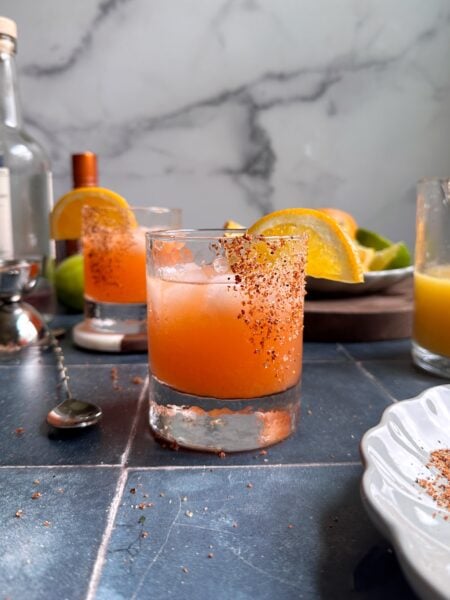 glass of orange aperol margarita with tajin rim