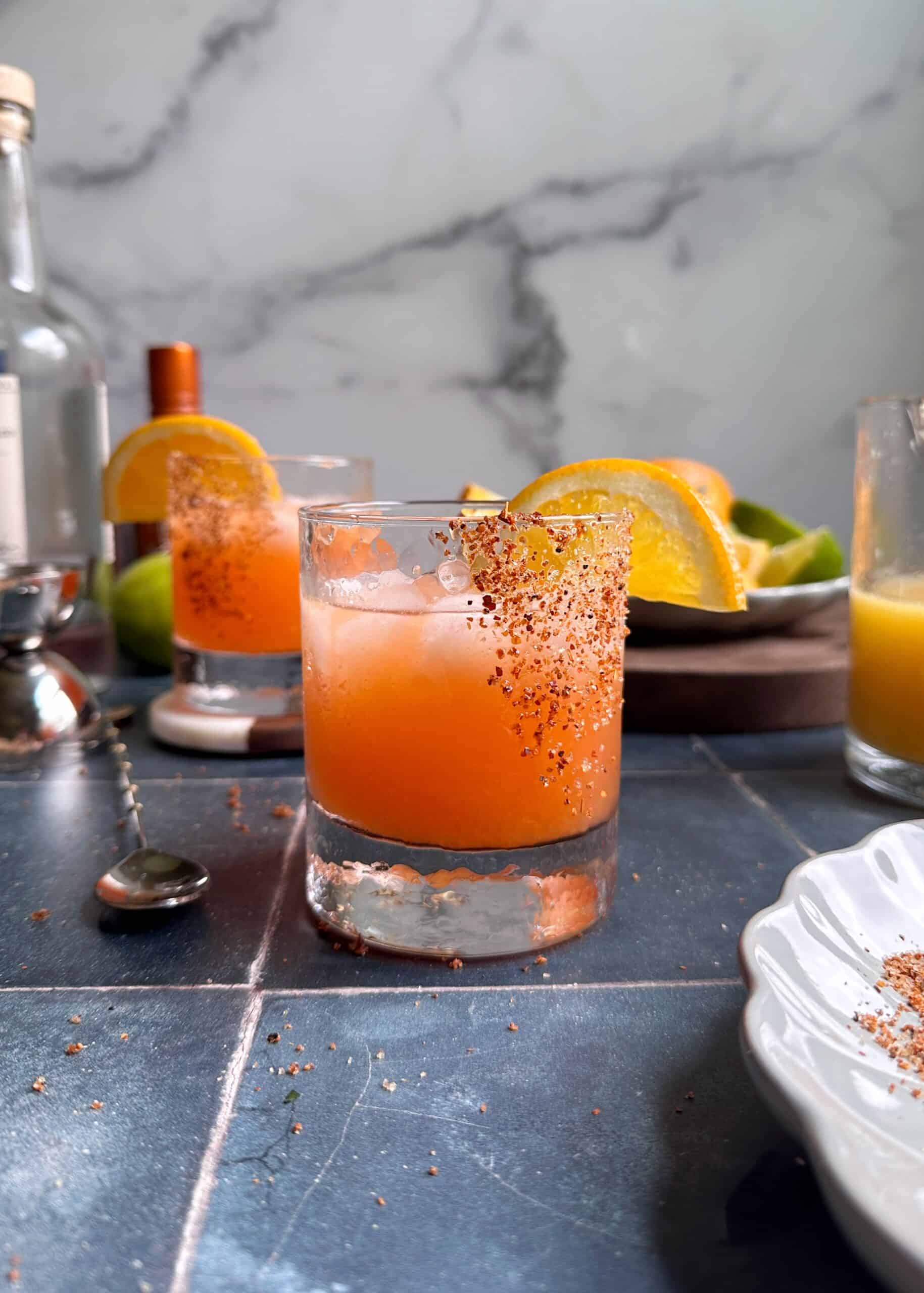 glass of orange aperol margarita with tajin rim