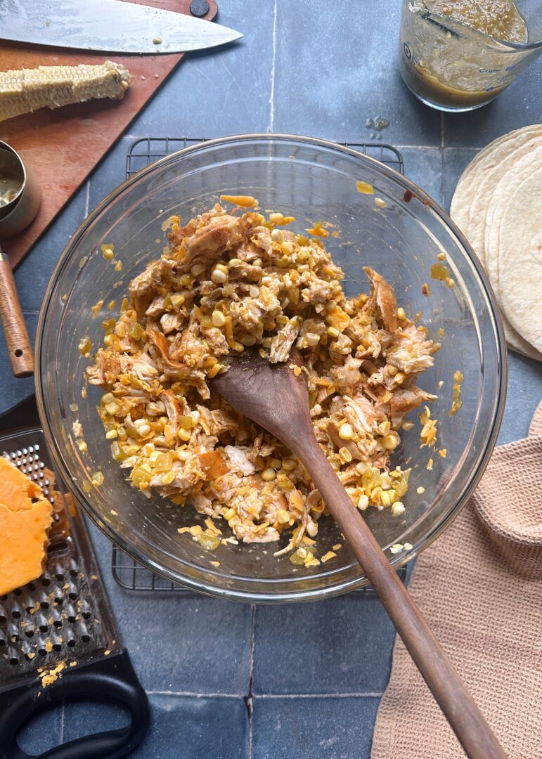 green chile chicken enchilada filling in glass mixing bowl