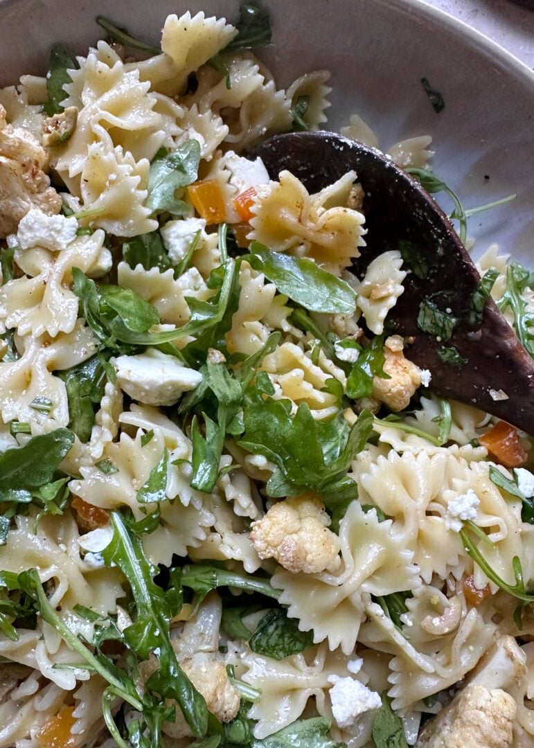 pasta salad with cauliflower olives and apricots with a wooden serving spoon