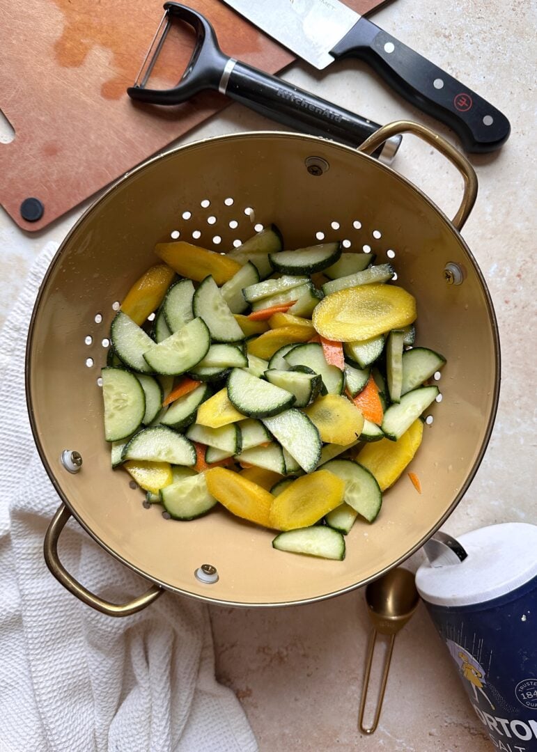 sliced carrots and cucumber in a colander
