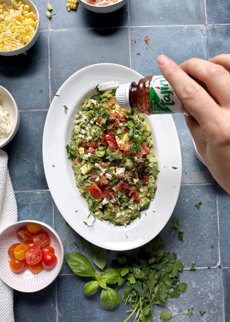 sprinkling tajin on loaded guacamole