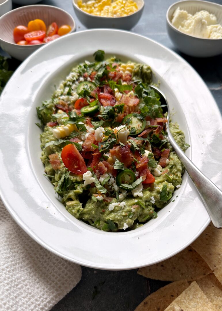 summer produce loaded guacamole in white serving bowl