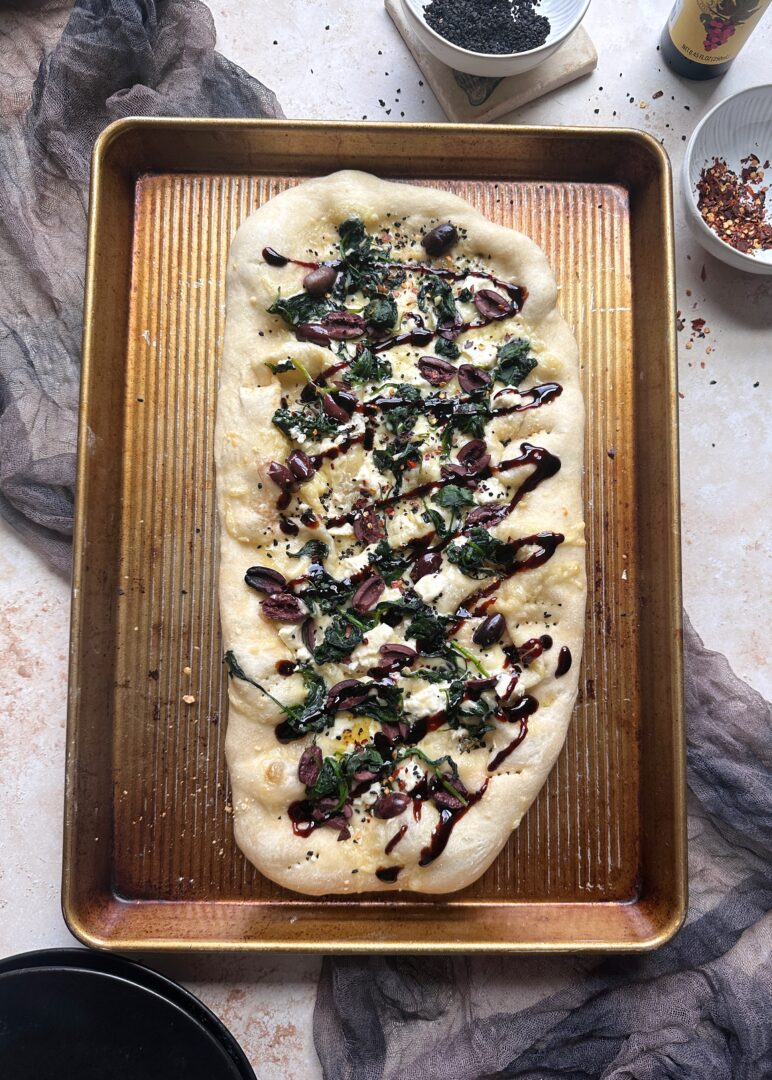 baked spinach kalamta olive and black garlic pizza with balsamic drizzle