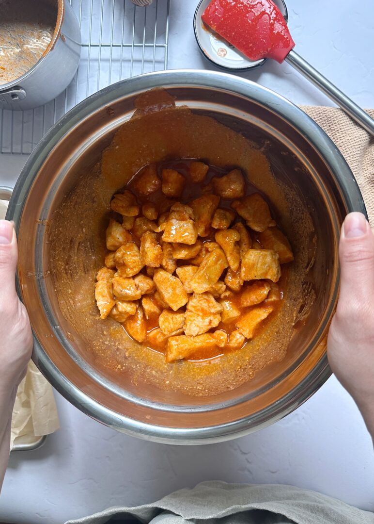 boneless wings tossed in buffalo sauce in silver mixing bowl
