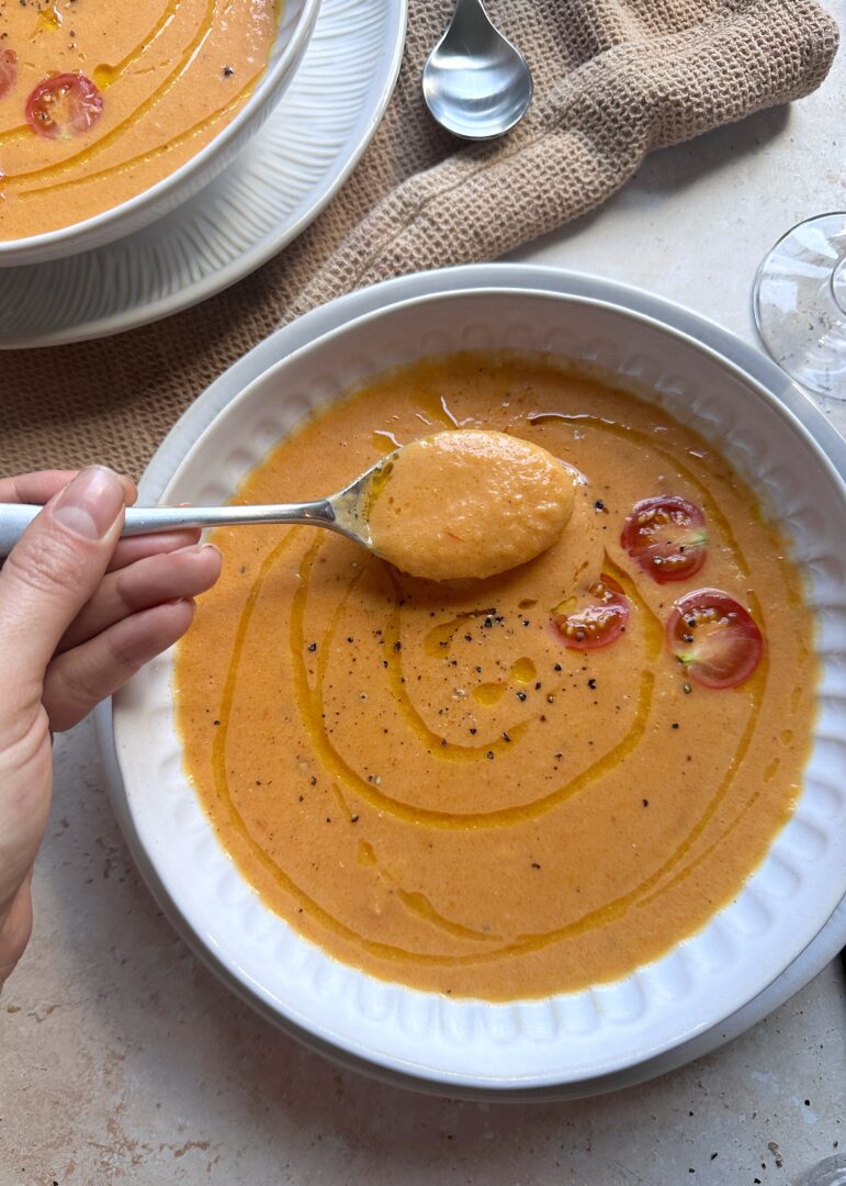 bowl and spoon of roasted tomato and butternut squash sopu