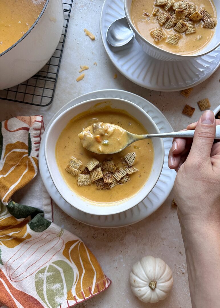 bowl of pumpkin beer cheese soup with chili maple chex with a spoonful of soup