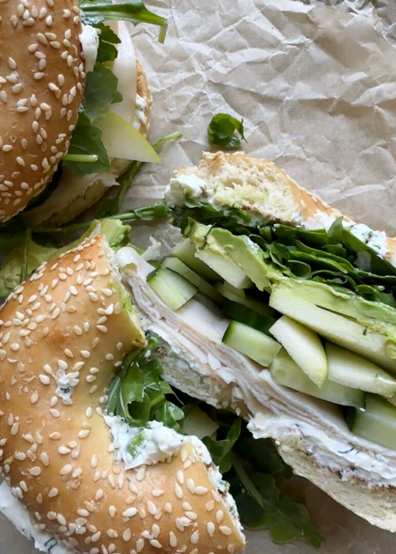 cross section of mean green vegetable bagel sandwich with slices of turkey