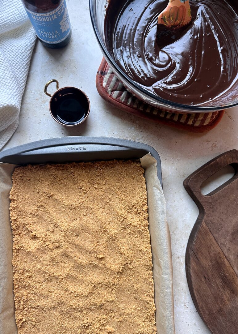 graham cracker crust pressed into baking pan with bowl of chocolate mousse on the side