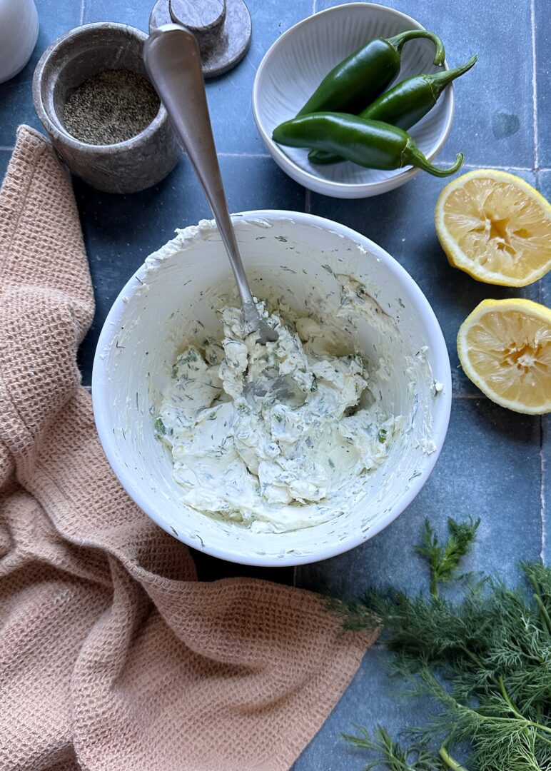 jalapeno herb cream cheese in a white mixing bowl with silver spoon