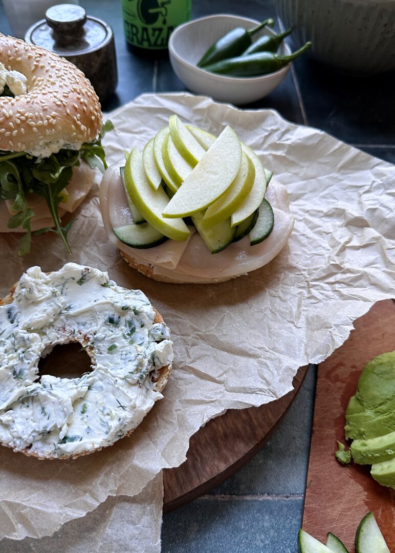 open face green vegetable bagel sandwich with herby cream cheese