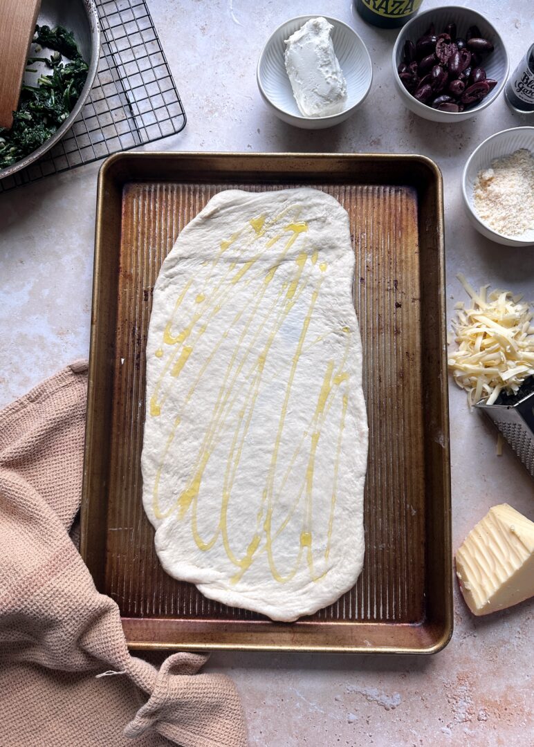pizza crust drizzled with olive oil on baking sheet