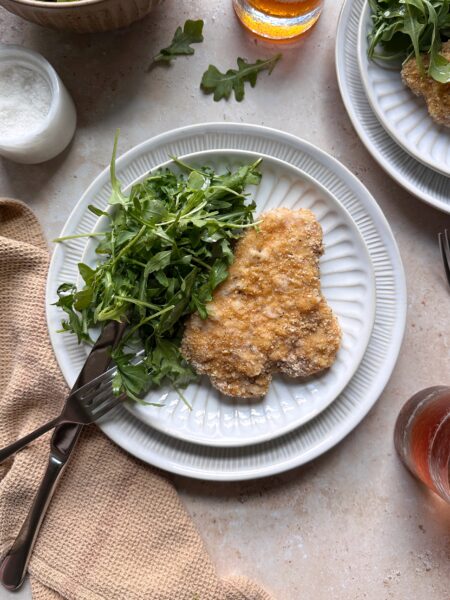 plate of baked pork schnitzel with arugula salad