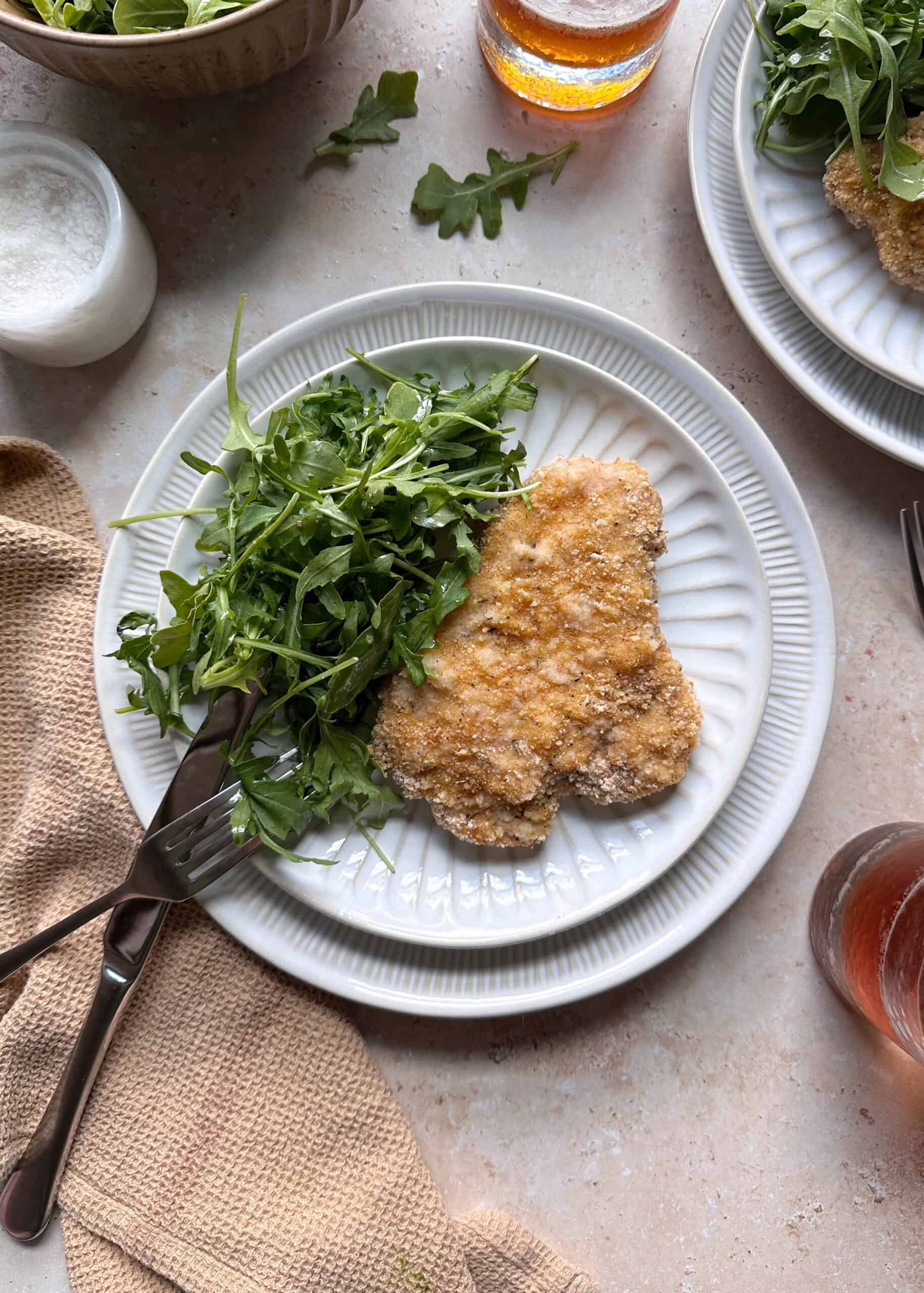 plate of baked pork schnitzel with arugula salad