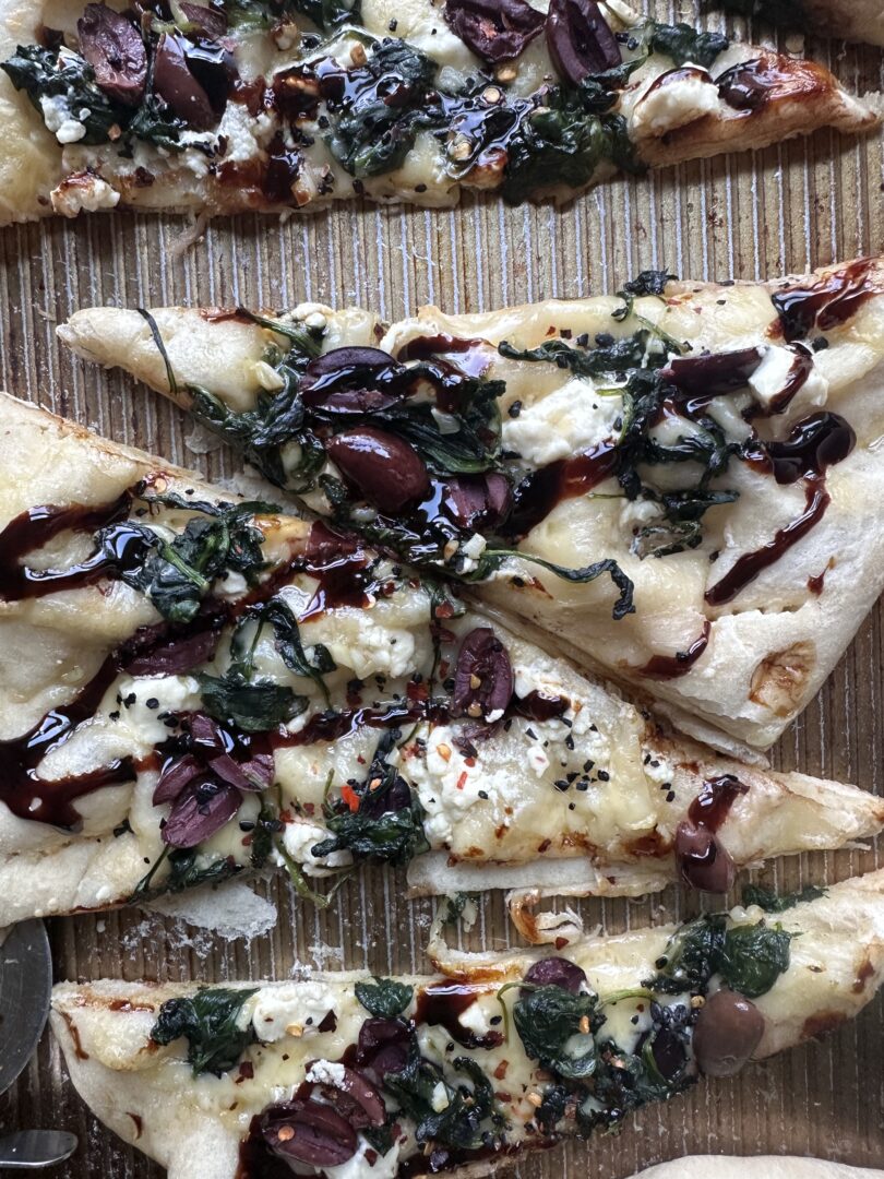 spinach kalamata olive and black garlic pizza with balsamic drizzle