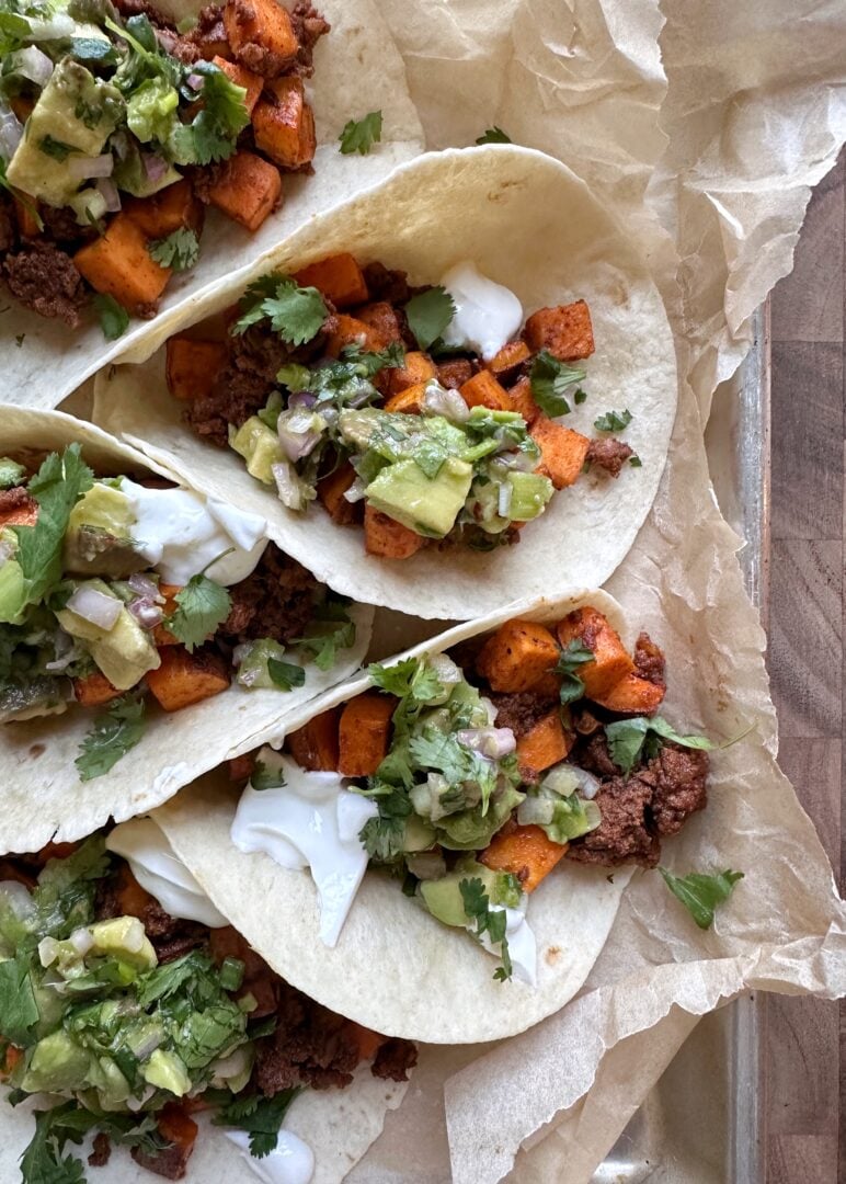 sweet potato chorizo tacos with lime crema and avocado salsa on a tray