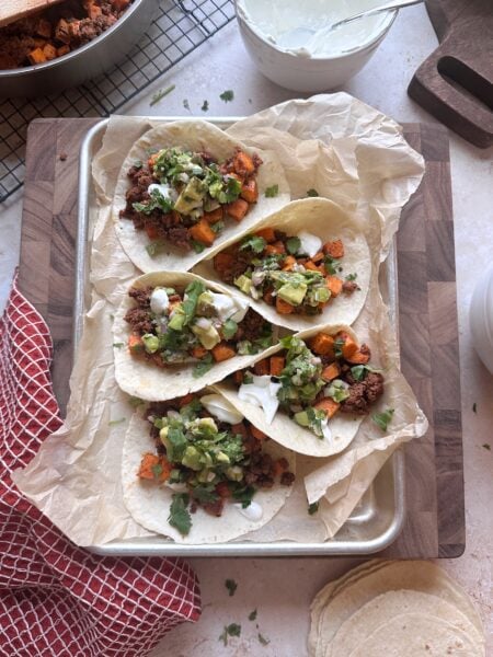 tray of chorizo sweet potato tacos with lime crema and avocado salsa