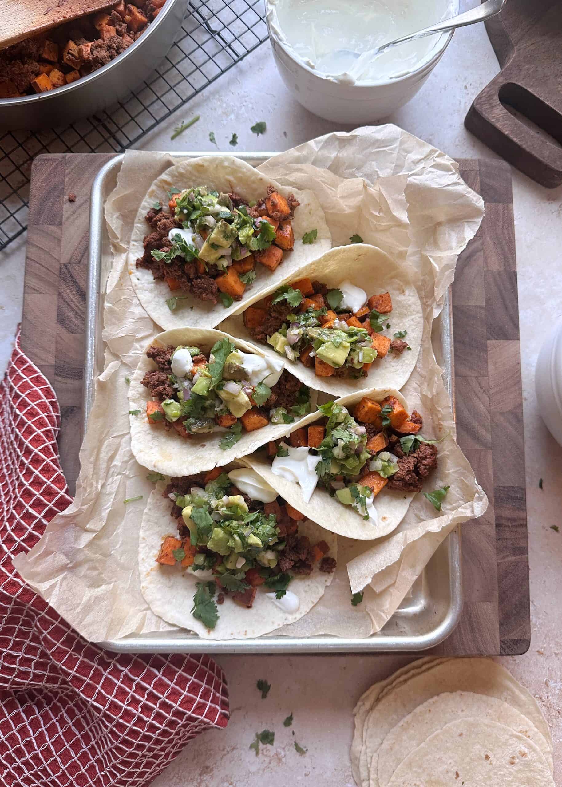 tray of chorizo sweet potato tacos with lime crema and avocado salsa