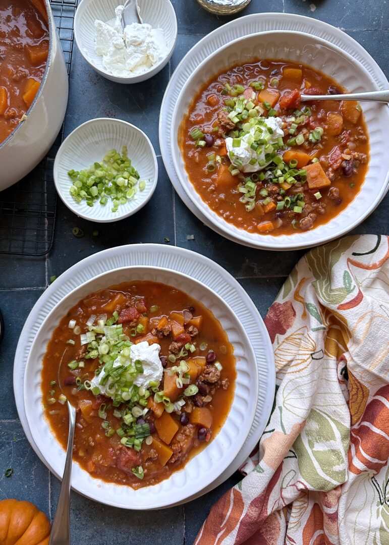 two bowl of autumn harvest chili with sour cream and green onion garnish