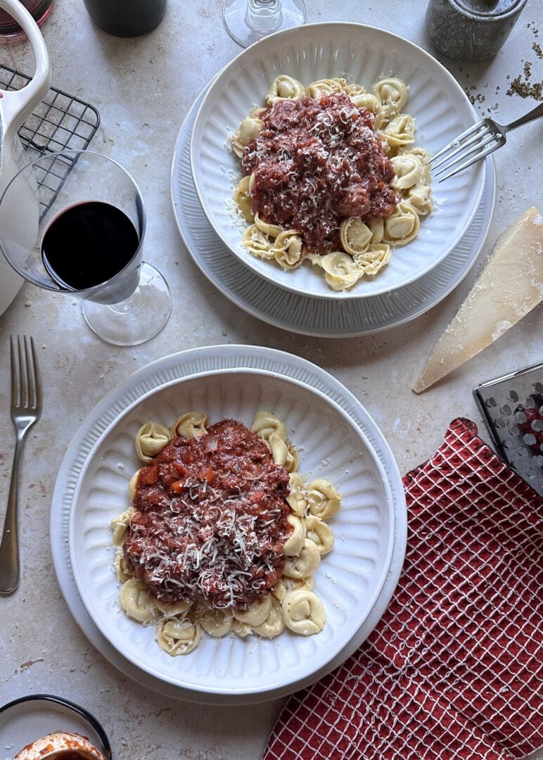 two bowls of brown butter tortellini bolognese with parmesan garnish