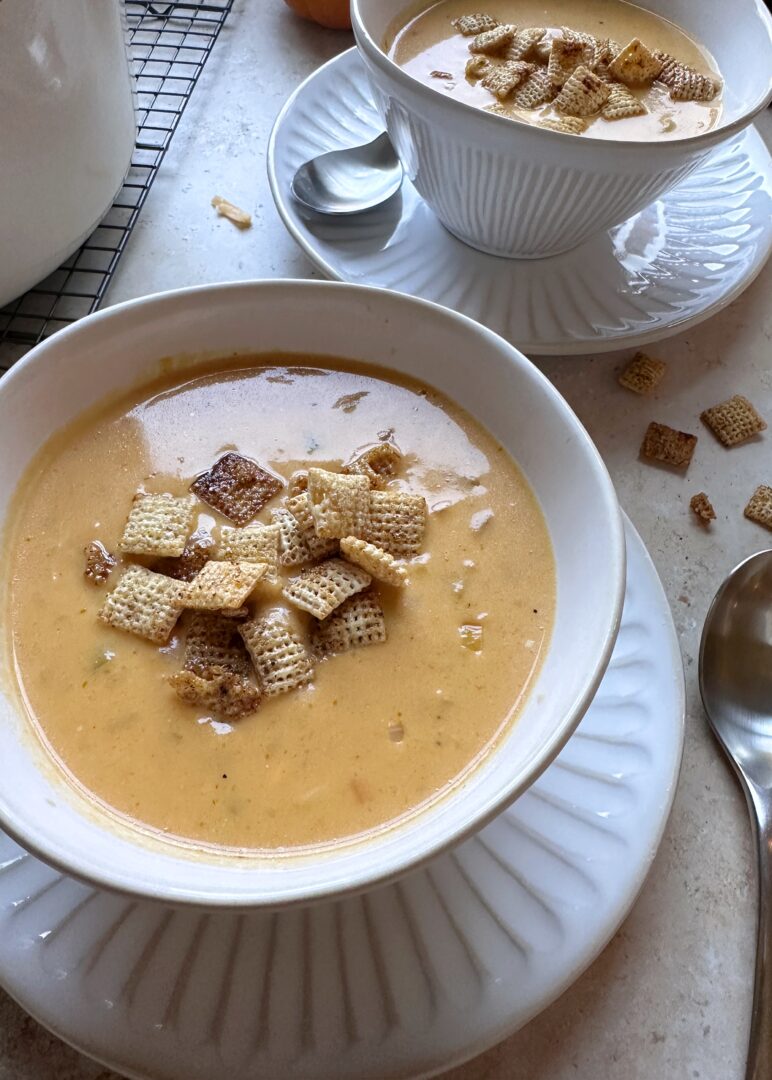 two bowls of pumpkin beer cheese soup with chili maple chex