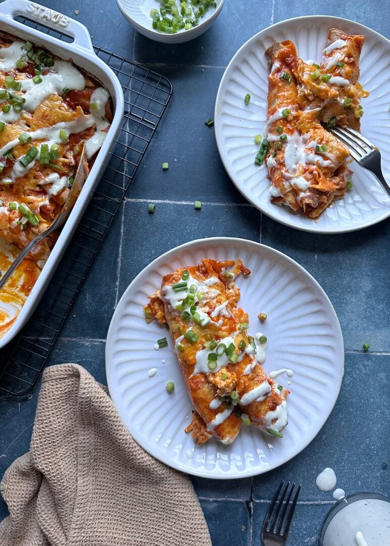 two plates of buffalo chicken enchiladas with ranch dressing and green onion