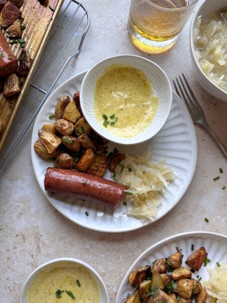 two roasted pieces of kielbasa with potatoes and honey mustard