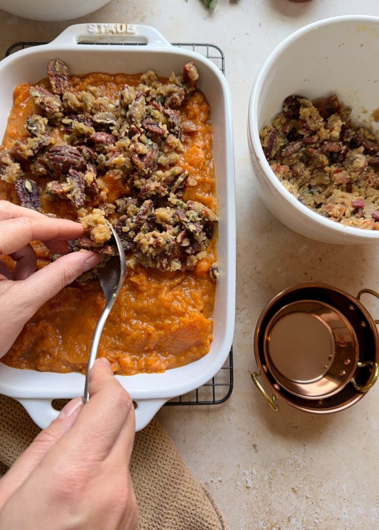 arranging the brown sugar bacon pecan topping on sweet potato casserole with bourbon