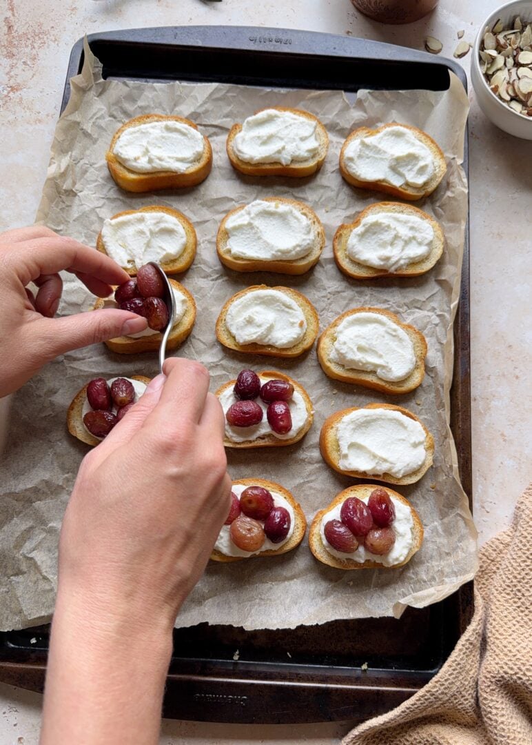 assembling roasted grape crostini with lemony ricotta