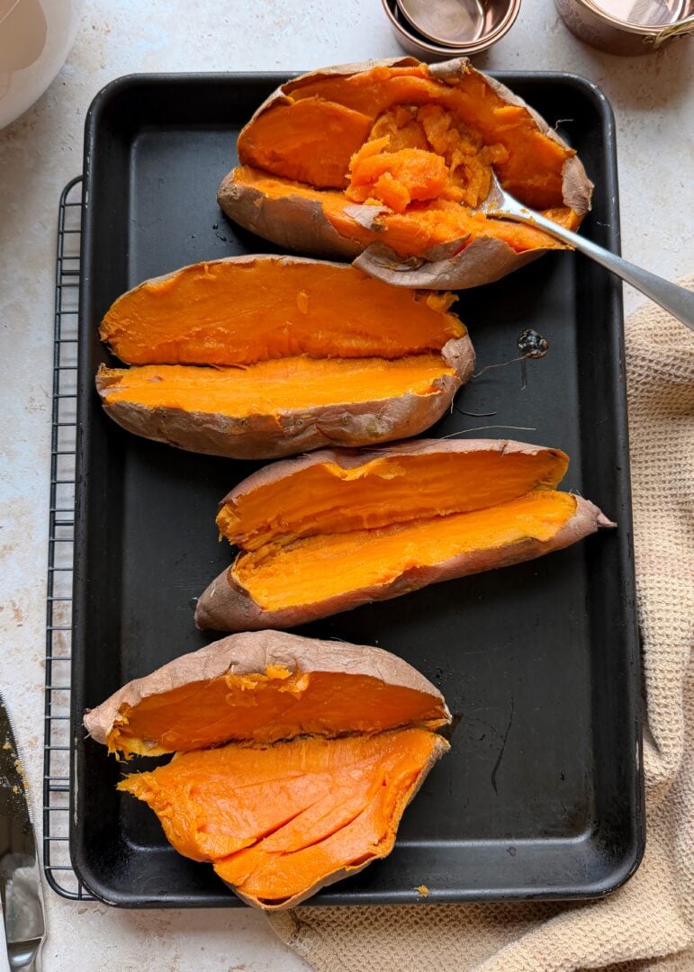 baked sweet potatoes on a tray cut in half