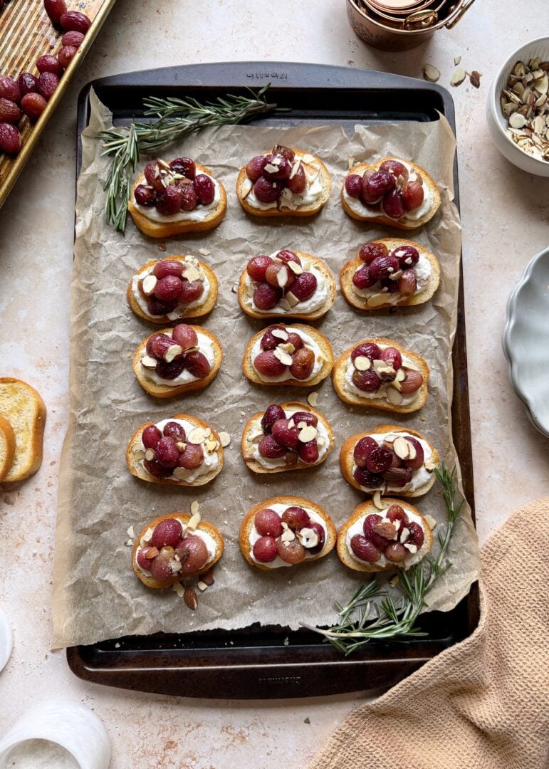 baking sheet of roasted grape crostini with ricotta and almonds