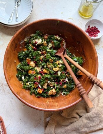 bowl of roasted chicken sprouts sweet potato and kale salad with wooden salad tongs