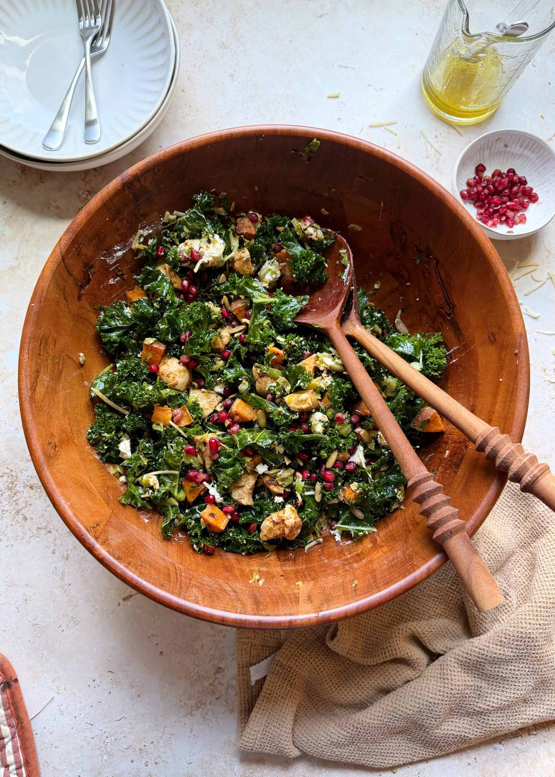 bowl of roasted chicken sprouts sweet potato and kale salad with wooden salad tongs