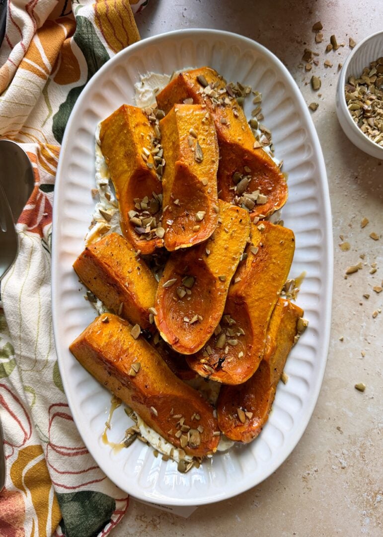 plate of roasted honeynut squash with goat cheese and pumpkin seeds