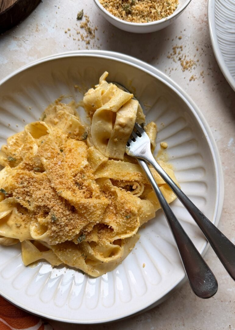 pumpkin alfredo in a bowl wrapped around a silver spoon