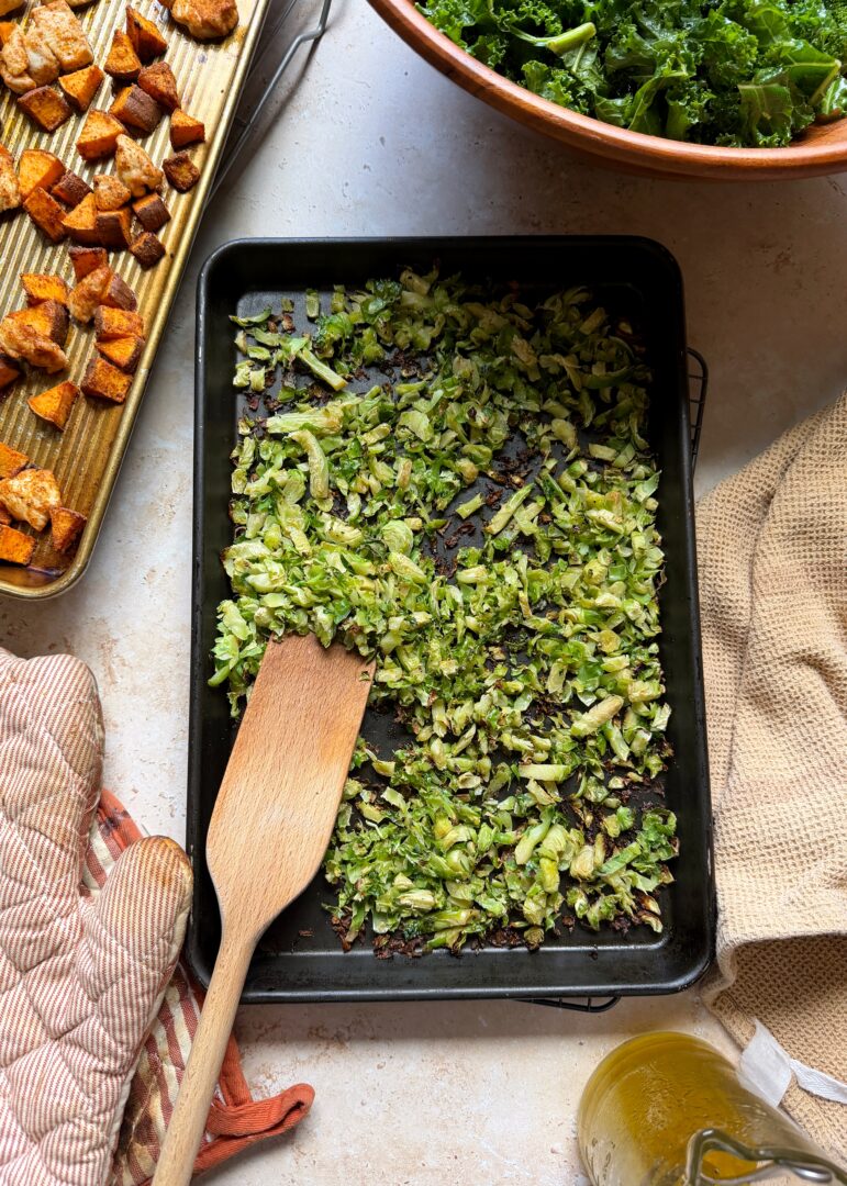 roasted brussels sprouts on a tray with wooden spatula