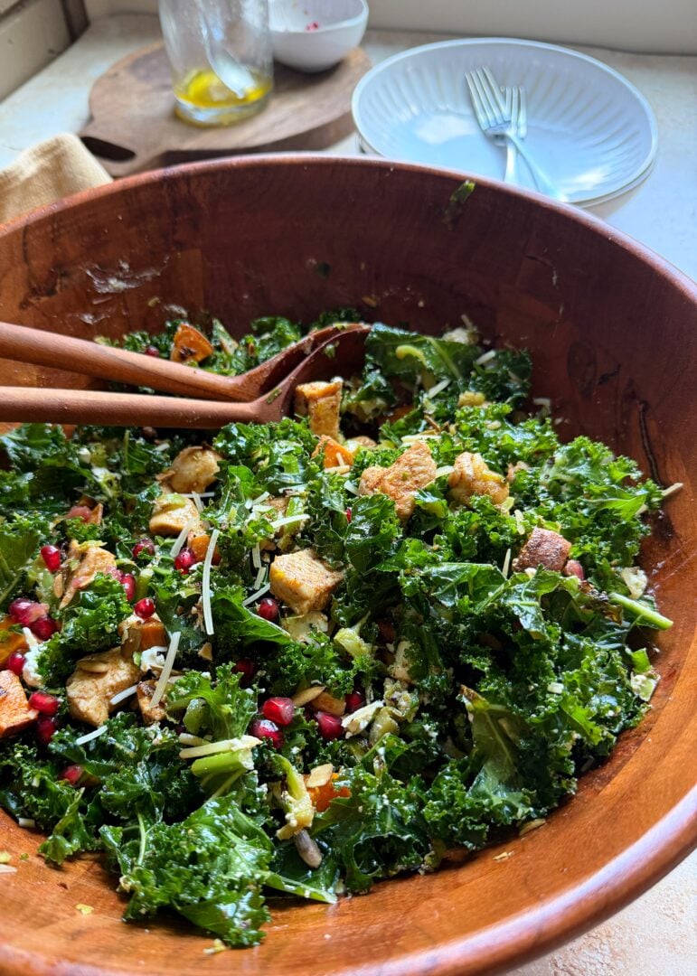 roasted sprout sweet potato and kale salad with maple dressing in wooden bowl