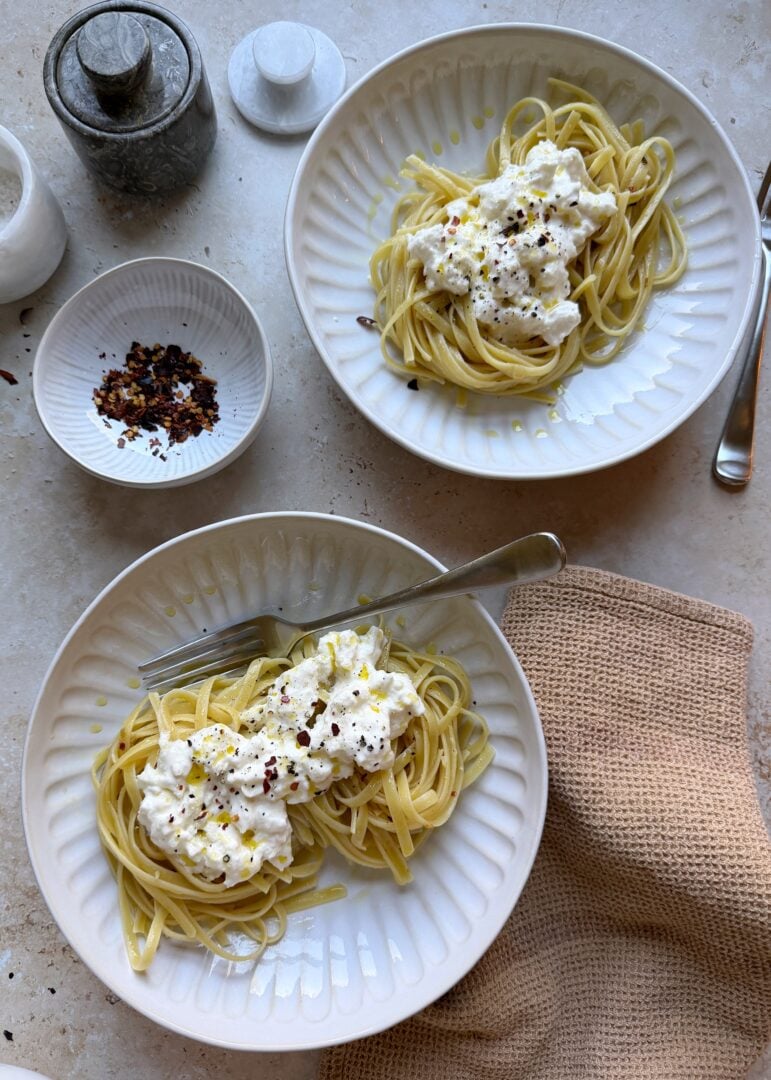 two bowls of stracciatella pasta with red pepper flakes on the side