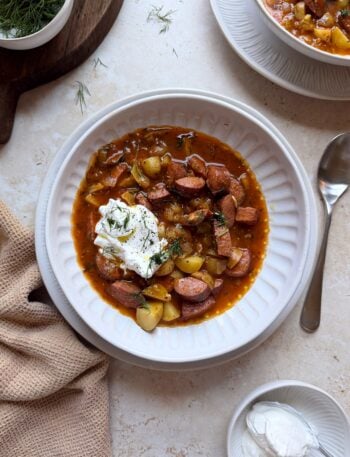 bowl of kielbasa potato soup with sour cream and dill