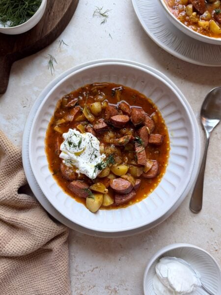 bowl of kielbasa potato soup with sour cream and dill