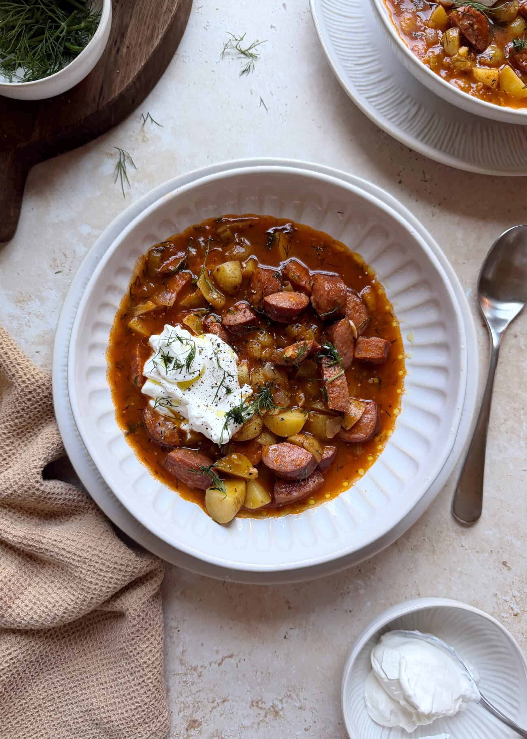 bowl of kielbasa potato soup with sour cream and dill