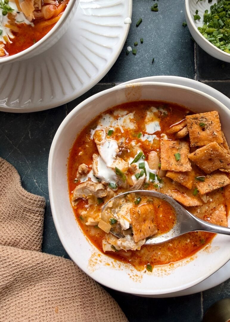 bowl of buffalo chicken white chili with ranch and chives on top