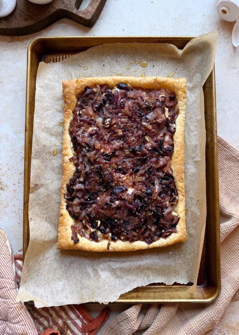 caramelized onion and boursin tart out of the oven on a baking sheet