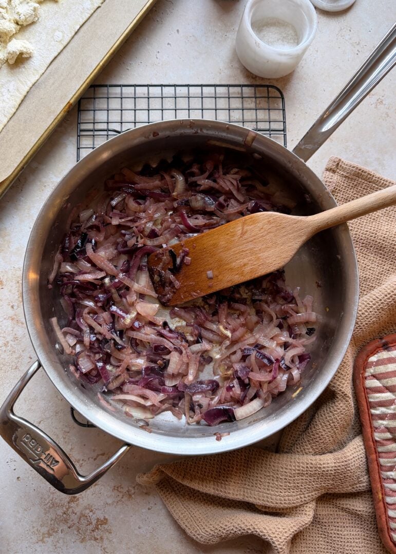 caramelized onions in large saute pan with wooden spatula
